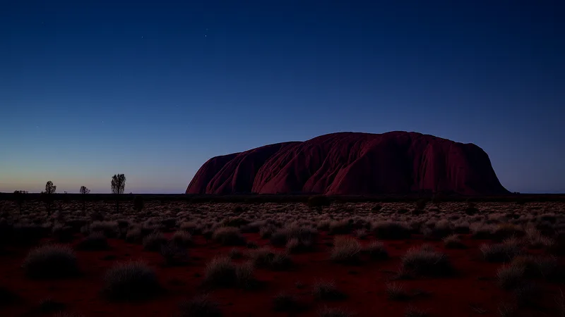 Uluru at blue hour beside a deep indigo winter sky with a faint green afterglow