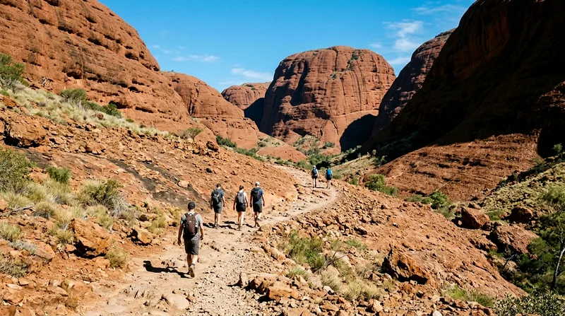 Five hikers walking rocky trail surrounded by tall red rock domes.