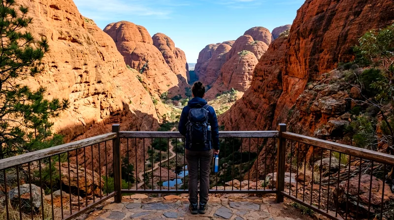 Lone walker at lookout viewing narrow red gorge between Kata Tjuta domes.